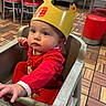 Freya joined the competition — help win amazing prizes! baby, child, burger_king, crown, high_chair, red_clothing, restaurant, floor_tiles, wooden_chairs, red_stools, indoor, curious, seated, infant, fast_food, table, person, cute, dining_area, casual