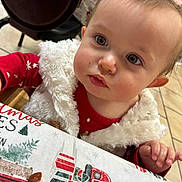 Freya joined the competition — help win amazing prizes! toddler, child, face, curious, red_clothing, white_vest, tablecloth, holiday_theme, indoor, floor_tiles, chair, hand, expression, portrait, young_child, cute, person, baby, festive, closeup
