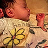 baby, sleeping, blanket, flower_pattern, cozy, infant, child, portrait, side_profile, soft_lighting, cute, peaceful, hand, clothing, indoors, warm_colors, face, newborn, resting, toddler
