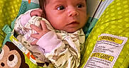Daenerys is registered to the contest to win money with this photo: baby, infant, blanket, monkey, pattern, green, cushion, warning_label, clothing, hand, face, eyes, curious, alert, indoors, colorful, fabric, soft_toys, child, portrait