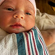 Daenerys is registered to the contest to win money with this photo: baby, newborn, infant, closeup, face, pink_hat, striped_blanket, wrapped, skin, portrait, cute, child, soft, warm_lighting, expression, eyes, mouth, nose, sleeping_area, cozy