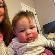 Rowen is registered to the contest to win money with this photo: baby, child, indoor, person, face, rosy_cheeks, striped_clothing, holding, adult, door, furniture, curious, close_up, portrait, cozy, home, hand, long_hair, woman, casual