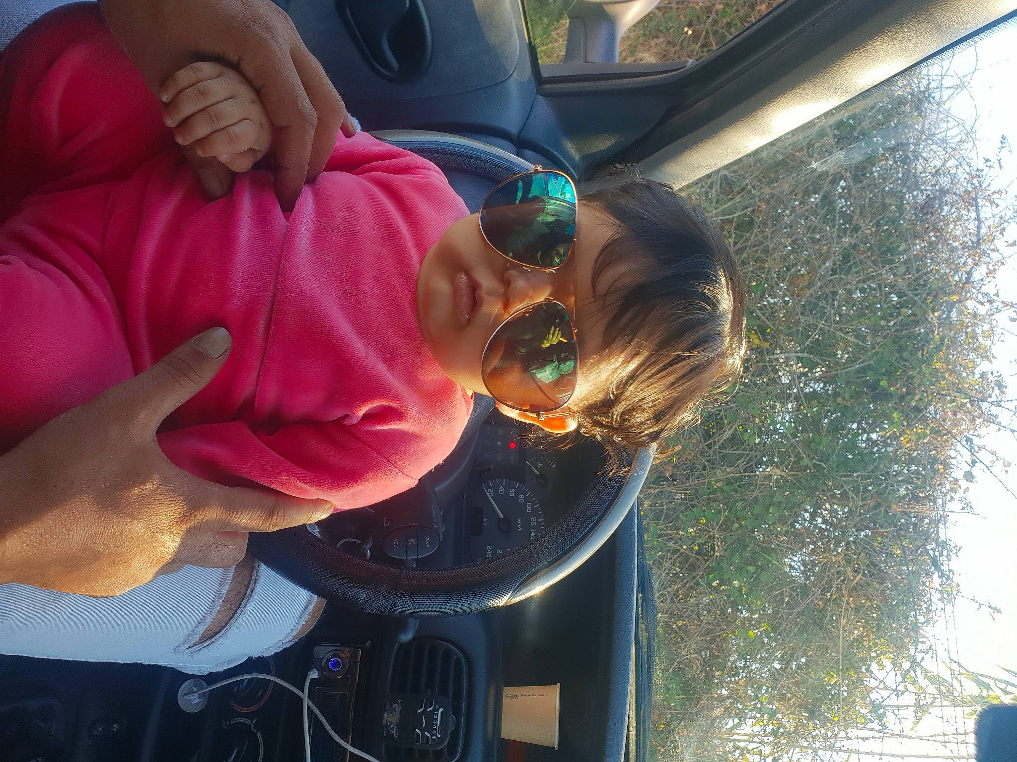 Amira participe au concours pour gagner de l'argent avec cette photo : auto_part, automotive_exterior, automotive_lighting, automotive_window_part, car, child, eyewear, family_car, fun, gesture, glass, goggles, person, sunglasses, thumb, toddler, tree, vehicle_door, vision_care, window