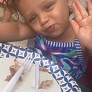 Anayaaracely Ginorio is registered to the contest to win money with this photo: child, curly_hair, waving, smiling, paper_plate, plastic_forks, food_leftovers, outdoor, casual, meal, colorful_clothing, person, face, happy, table, summer, daylight, closeup, fun, cute