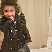 Gioia Maria participe au concours pour gagner de l'argent avec cette photo : child, curly_hair, black_coat, indoor, bed, smiling, playful, person, curtain, buttoned_coat, fashion, cute, portrait, young, happy, standing, fingertip, light_skin, casual, room