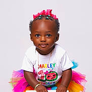 Marley is registered to the contest to win money with this photo: accessory, birthday, braided_hair, bright_colors, celebration, chair, child, colorful_tutu, cute, fashion, gold_bracelet, happy, pink_bow, portrait, posing, smiling, studio_photo, toddler, white_background, white_shirt