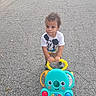 asphalt, blue_wheels, casual_clothing, child, colorful_toy, cracked_pavement, curly_hair, cute, daylight, mickey_mouse, numbers, outdoor, playtime, sidewalk, toddler, toy_walker, tshirt, walking_toy, yellow_handle, young_child