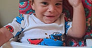 D Angelo is registered to the contest to win money with this photo: baby, burger_king_crown, child, clothing, colorful, cute, face, food_crumbs, hand, happy, high_chair, indoor, messy, person, portrait, seat, smiling, toddler, tray, young_child