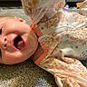 baby, infant, smiling, happy, face, mouth_open, carpet, floor, clothing, sleeper, floral_pattern, child, cute, indoors, playful, person, skin, head, expression, young