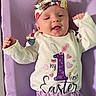 Oakley is registered to the contest to win money with this photo: baby, infant, child, headband, purple_blanket, white_shirt, easter, smiling, happy, cute, portrait, lying_down, celebration, clothing, toddler, pastel_colors, hands, face, indoors, expression