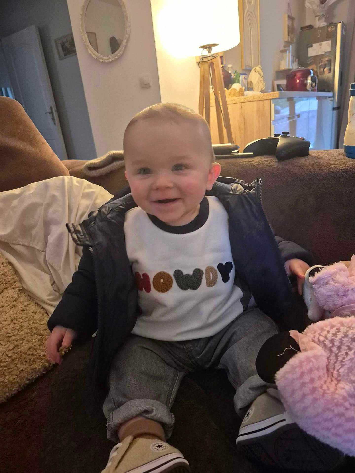 Loan a rejoint le concours — aidez-le/la à gagner de superbes lots ! baby, child, smiling, jacket, jeans, sneakers, indoor, couch, toy, stuffed_animal, lamp, living_room, happy, person, seated, furniture, home, cozy, casual_clothing, portrait