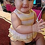 baby, child, smiling, headband, dress, sitting, clapping, carpet, indoors, cute, joyful, pastel_colors, furniture, television, sock, chubby_cheeks, portrait, young_child, happy, person