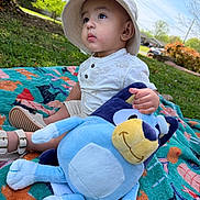 Ethan joined the competition — help win amazing prizes! toddler, child, baby, hat, plush_toy, blue, blanket, outdoor, grass, sunlight, greenery, park, summer, cute, sitting, portrait, nature, toy, happy, daytime
