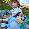 toddler, child, baby, hat, plush_toy, blue, blanket, outdoor, grass, sunlight, greenery, park, summer, cute, sitting, portrait, nature, toy, happy, daytime