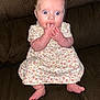 baby, child, infant, dress, floral_pattern, sitting, couch, fingers_in_mouth, red_eye, wide_eyes, cute, indoors, person, footwear_off, barefoot, expression, skin, hands, legs, seat