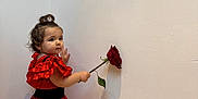 Milena a rejoint le concours — aidez-le/la à gagner de superbes lots ! toddler, child, girl, red_dress, polka_dot, flamenco_style, rose, flower, wall, curly_hair, top_knot, indoor, portrait, person, cute, standing, holding, flower_stem, shadow, soft_lighting