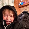 Levi joined the competition — help win amazing prizes! child, smiling, hoodie, black_jacket, indoor, wooden_wall, shelf, bottles, happy, face, person, clothing, portrait, young_child, laughing, zipper, hair, casual, cozy, background