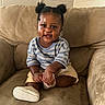 Tripp is registered to the contest to win money with this photo: child, toddler, baby, smiling, sitting, portrait, couch, indoors, living_room, hair_buns, striped_shirt, shorts, sneakers, clothing, furniture, happy, face, looking_at_camera, home, photography