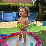 Eymen a rejoint le concours — aidez-le/la à gagner de superbes lots ! backyard, balls, blue_chair, child, curly_hair, daytime, grass, green, hedge, house, inflatable_pool, outdoor, plastic, play, summer, sunny, swimwear, toddler, toy, water