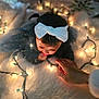Caleigh is registered to the contest to win money with this photo: baby, child, white_bow, christmas_lights, glowing_lights, curious, hand, fluffy_rug, holiday, indoors, soft_lighting, cute, infant, dark_hair, toddler, warm, decorations, festive, cozy, portrait