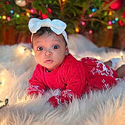 Caleigh is registered to the contest to win money with this photo: baby, infant, red_sweater, white_bow, christmas_tree, ornaments, holiday_lights, fluffy_rug, cute, curious, indoors, festive, decorations, child, christmas, winter_clothing, portrait, holiday_season, smiling, seasonal