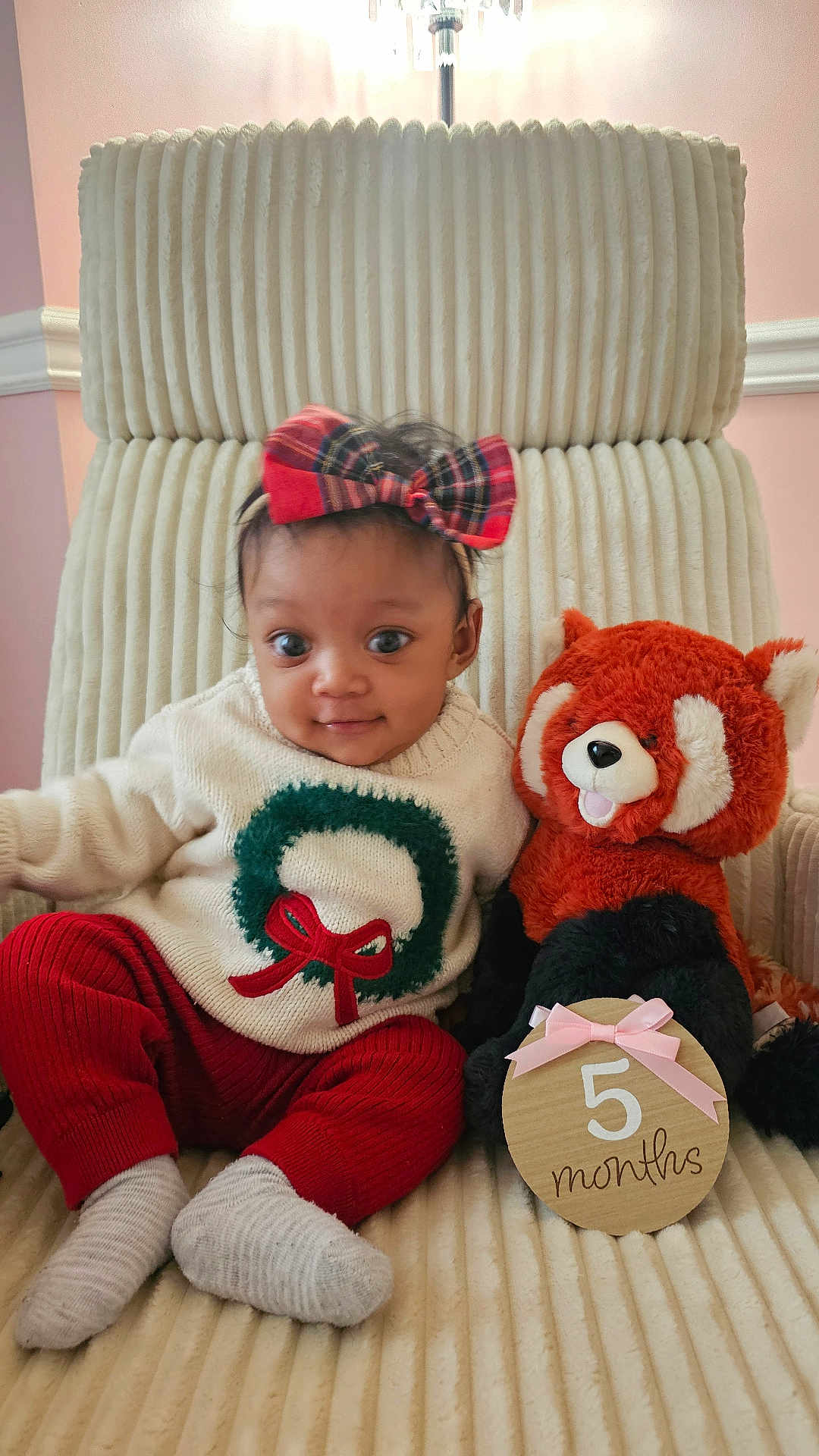 Caleigh is registered to the contest to win money with this photo: baby, child, plush_toy, red_panda, sweater, headband, bow, chair, milestone_sign, 5_months, red_pants, socks, indoor, cute, smiling, portrait, soft_texture, holiday_theme, decorative, young_child