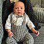 baby, infant, child, boy, clothing, bow_tie, suspenders, shirt, pants, socks, couch, pillow, indoor, portrait, sitting, cute, face, expression, home, furniture