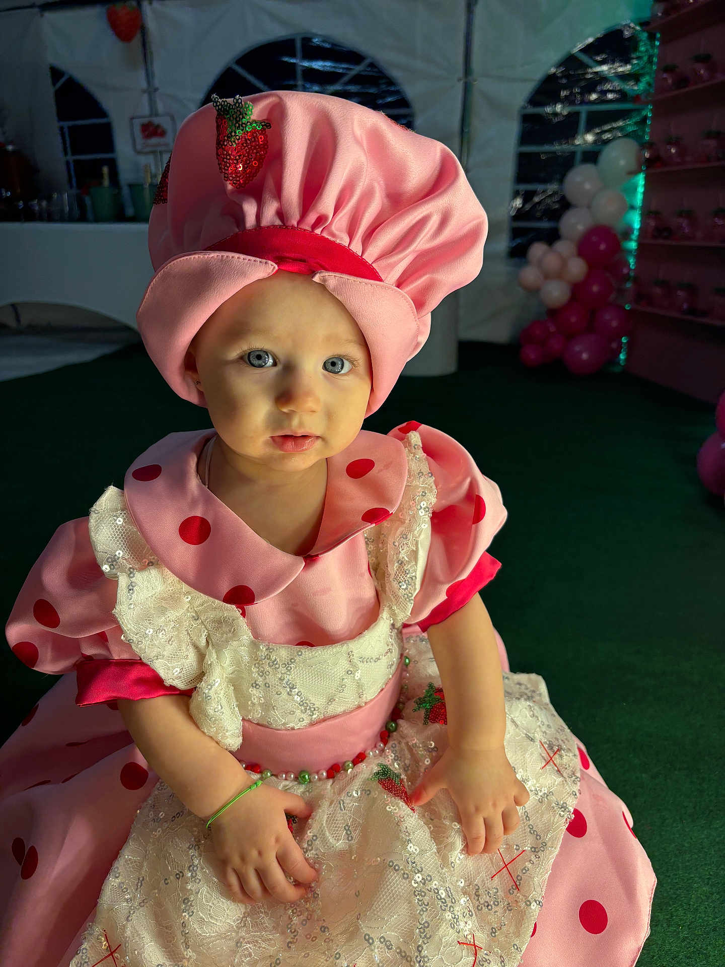 Kinaï participe au concours pour gagner de l'argent avec cette photo : toddler, child, costume, pink, polka_dot, bonnet, dress, party, indoor, balloons, face, blue_eyes, sequin, lace, green_carpet, tent, sitting, cute, portrait, celebration