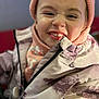 child, smiling, face, jacket, hat, knit_hat, winter_clothing, zipper, scarf, closeup, portrait, happy, cute, warm_clothing, indoor, young_child, playful, expression, person, cozy