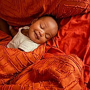 Jalen joined the competition — help win amazing prizes! baby, sleeping, smile, blanket, orange, texture, bed, comfort, rest, peaceful, infant, face, person, young_child, cozy, soft, relaxation, indoor, cushion, cute