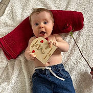 Paul a rejoint le concours — aidez-le/la à gagner de superbes lots ! baby, infant, blanket, towel, red_towel, rose, wooden_sign, hearts, denim_pants, blue_eyes, surprised_expression, lying_down, portrait, indoor, plush_blanket, milestone_card, monthly_milestone, hand, bare_torso, cute