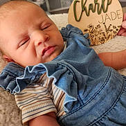 Charli is registered to the contest to win money with this photo: newborn, baby, sleeping, blue_outfit, striped_shirt, blanket, wooden_plaque, name_sign, indoor, closeup, infant, cute, soft_texture, resting, child, person, hand, decor, portrait, cozy