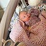 baby, blanket, crochet, playpen, toy, plush_toy, infant, child, indoor, curious, pink, floral_pattern, face, looking_up, soft_toys, hand, cozy, newborn, lying_down, colorful
