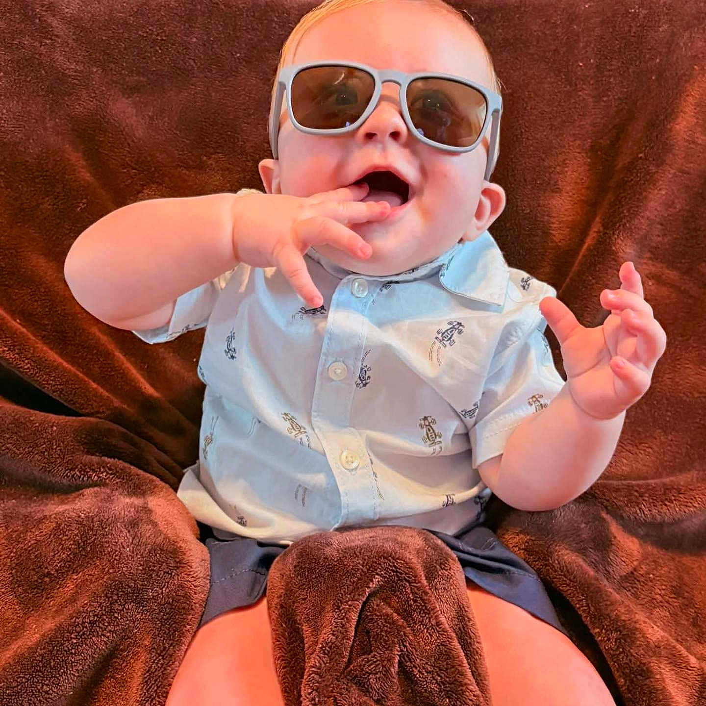 Derek is registered to the contest to win money with this photo: baby, blanket, brown_blanket, casual, child, comfort, cute, feet, hand, happy, indoor, infant, person, playful, portrait, relaxing, shirt, smiling, sunglasses, young_child