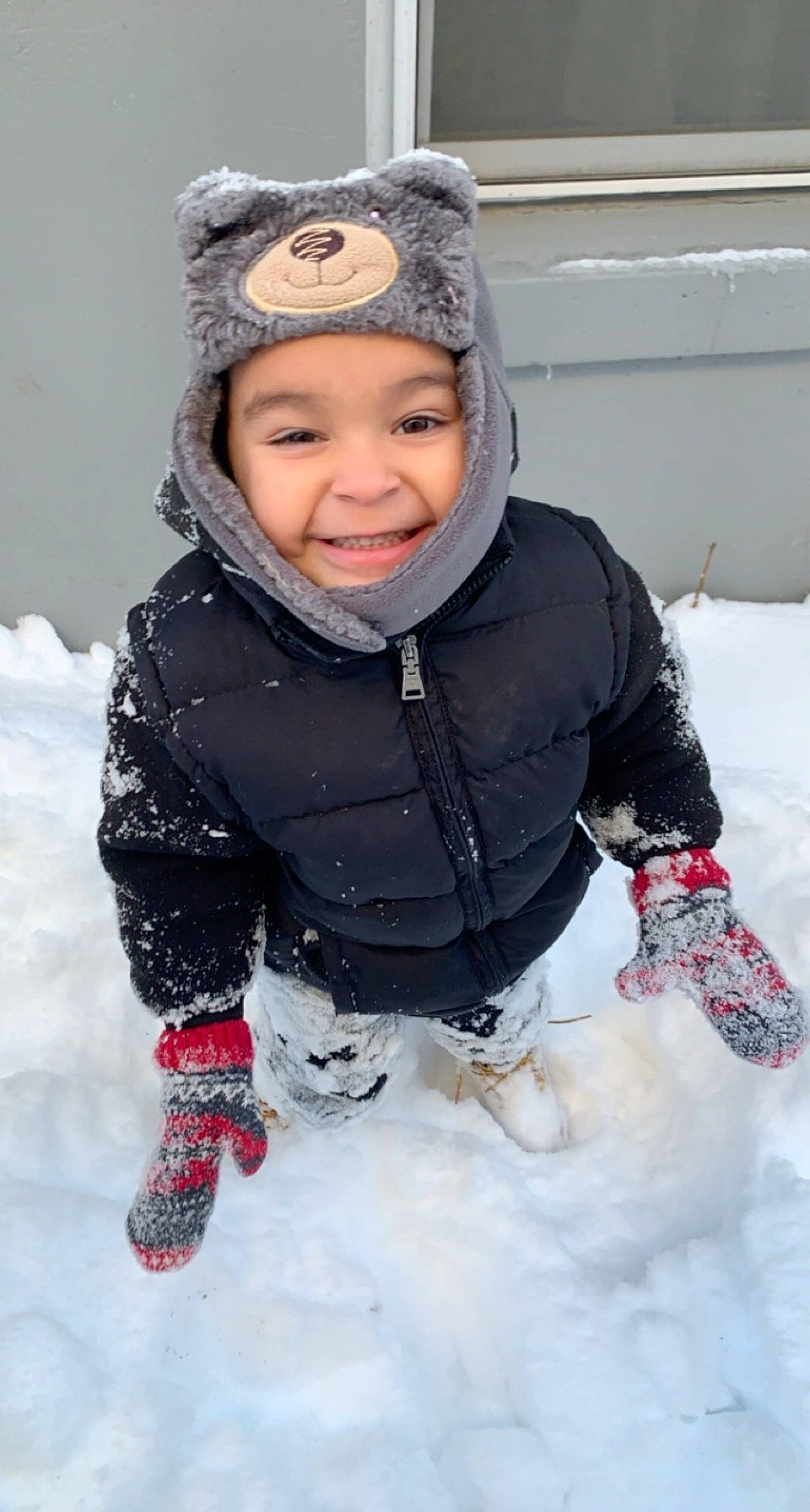 Enrique is registered to the contest to win money with this photo: baby_toddler_clothing, cap, cheek, child, face, freezing, fun, happy, headwear, jacket, joy, knit_cap, outerwear, parka, person, playing_in_the_snow, recreation, sitting, sleeve, smile