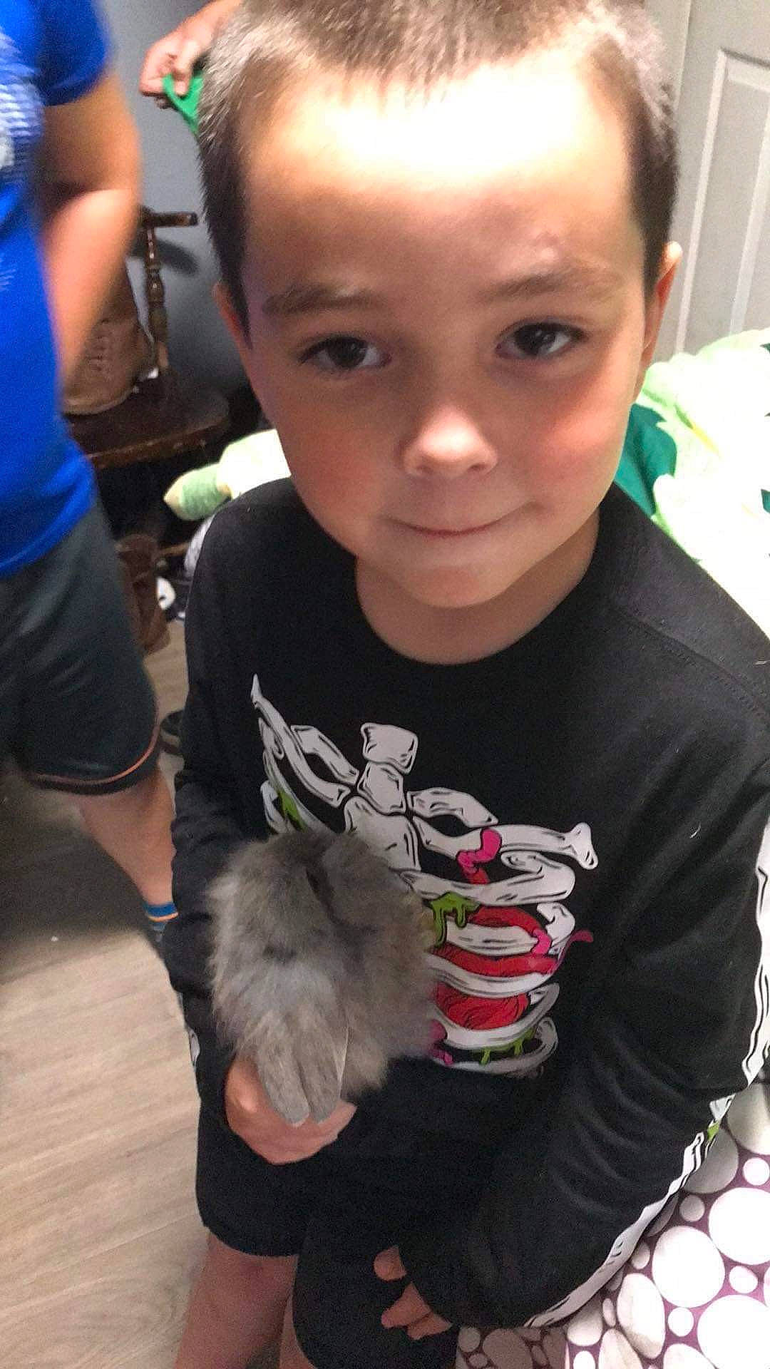 Theron is registered to the contest to win money with this photo: arm, child, companion_dog, ear, event, eye, eyelash, fun, fur, hairstyle, happy, iris, mammal, person, primate, rabbit, skin, sleeve, t_shirt, toddler