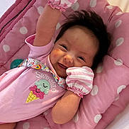 Madison is registered to the contest to win money with this photo: baby, smiling, pink, mittens, polka_dot, cushion, infant, cute, happy, lying_down, clothing, face, portrait, soft_toys, indoors, child, sweetie, ice_cream, striped, handwear