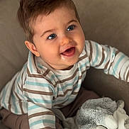 Nolan participe au concours pour gagner de l'argent avec cette photo : baby, blue_eyes, child, close_up, couch, cozy, cute, happy, indoor, infant, person, plush_toy, portrait, sitting, smiling, soft_toy, striped_shirt, stuffed_animal, warm_lighting, young_child