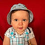 Raphaël participe au concours pour gagner de l'argent avec cette photo : baby, bucket_hat, car_patch, child, clothing, curious, cute, eyes, face, hat, indoor, infant, overalls, person, plaid, portrait, red_background, sitting, smiling, young_child