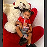 child, cute, doll, heart_shaped_chair, indoor, pigtails, playtime, plush, portrait, red_chair, red_shirt, shoes, sitting, smile, socks, stuffed_animal, teddy_bear, toddler, toy, young_child