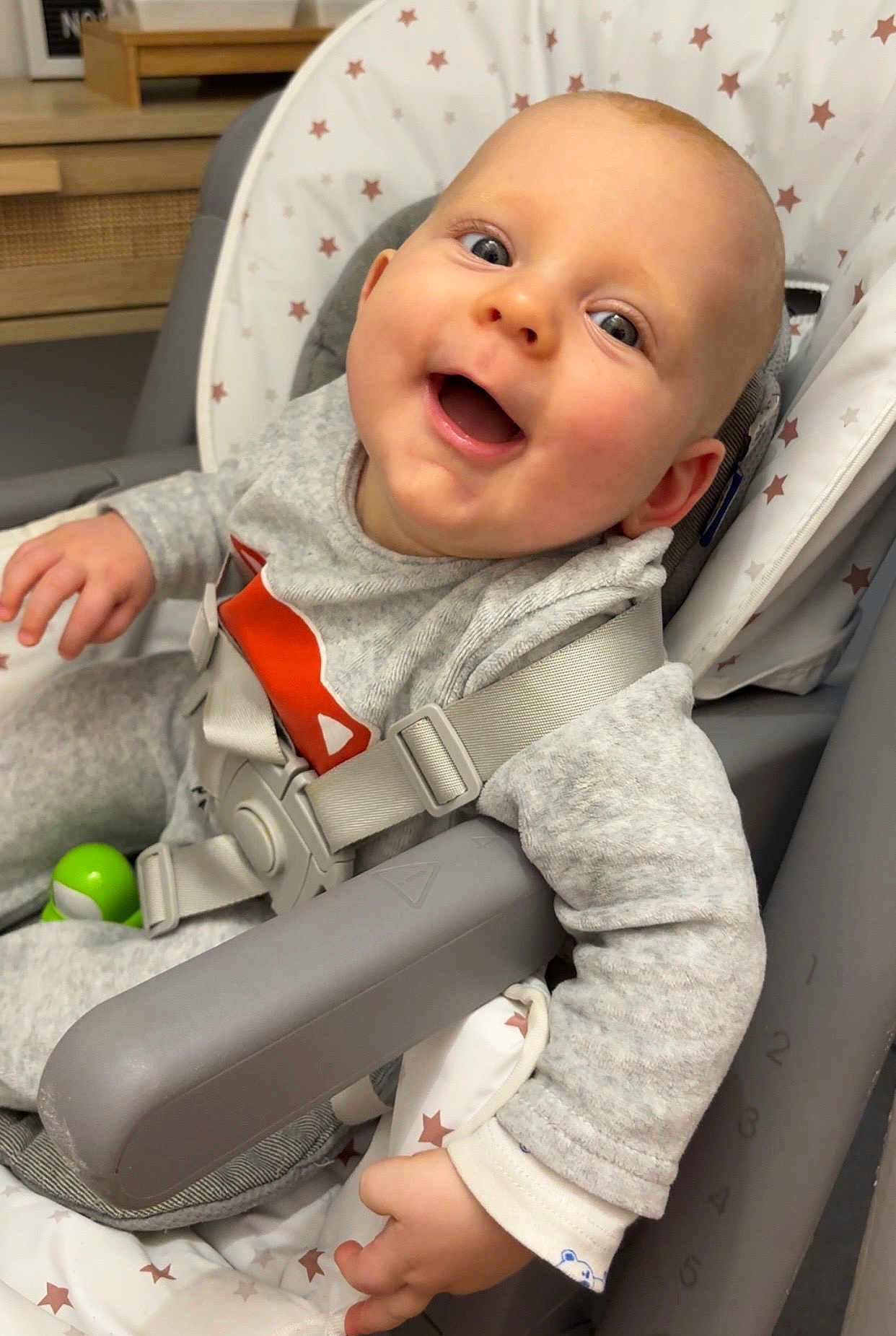 London a rejoint le concours — aidez-le/la à gagner de superbes lots ! baby, smiling, high_chair, straps, gray_clothing, star_pattern, indoor, happy, child, infant, face, hand, seat, toy, expression, cute, person, closeup, comfort, playful