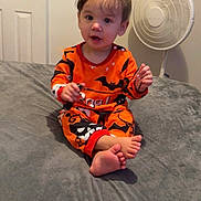 Madeleine joined the competition — help win amazing prizes! barefoot, bat_pattern, bed, bedroom, child, curly_hair, cute, door, expression, fan, gray_bedspread, halloween, holding_object, indoor, light_skin, orange_clothing, pajamas, sitting, toddler, young_child