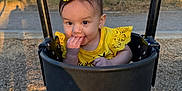 Madeleine is registered to the contest to win money with this photo: baby, child, cute, face, fun, metal_chains, nature, outdoor, park, person, playground, seat, shadow, smile, sunset, swing, toddler, tree, yellow_bow, yellow_clothing