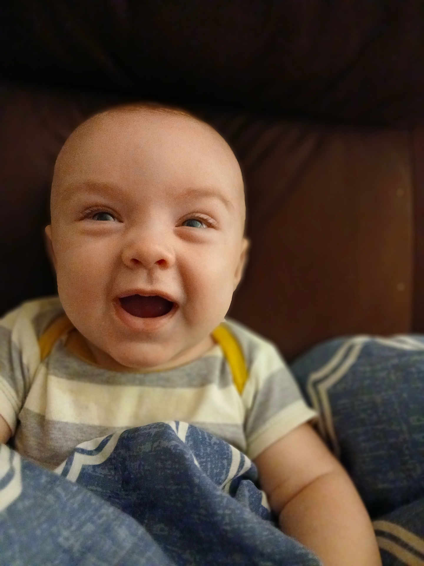 Asher is registered to the contest to win money with this photo: baby, smiling, happy, face, child, blanket, blue, striped_clothing, sitting, portrait, infant, cute, cozy, indoors, young_child, human, skin, head, eyes, mouth