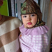 Iris a rejoint le concours — aidez-le/la à gagner de superbes lots ! toddler, child, person, hat, camouflage, sweater, purple, indoor, portrait, baby, face, curious, ruffled_collar, holding, adult, cozy, warm_clothing, looking, closeup, cute