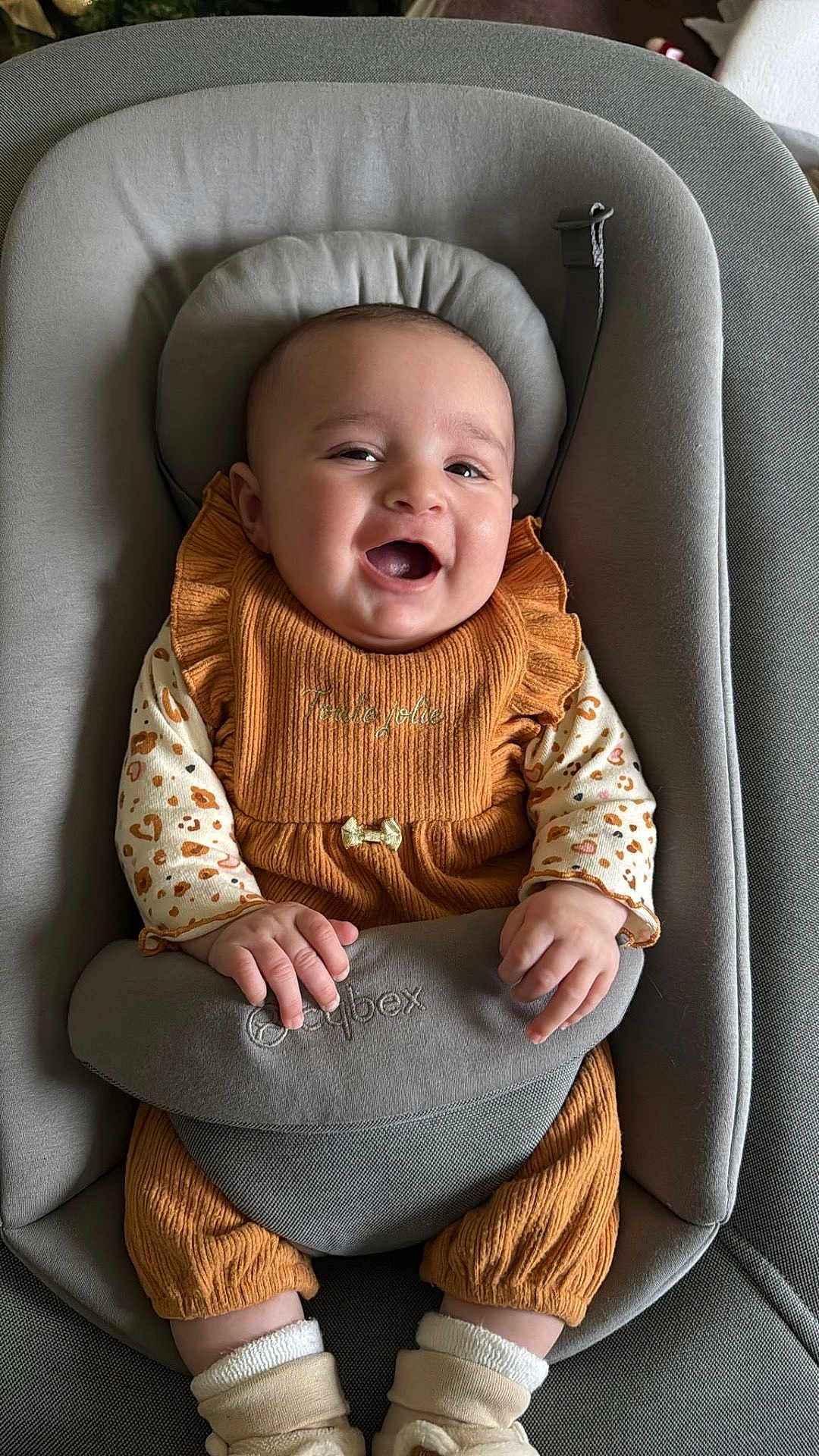 Janah a rejoint le concours — aidez-le/la à gagner de superbes lots ! baby, baby_accessory, baby_seat, child, clothing, cozy, cute, fabric, feet, footwear, hands, happy, indoors, infant, orange_clothing, portrait, seat, sitting, smiling, soft_texture