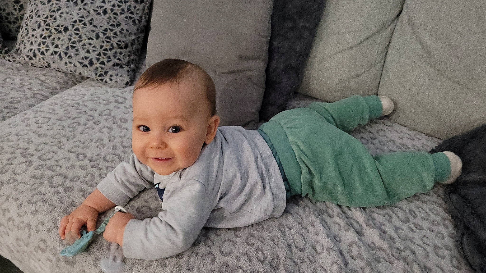 Tom participe au concours pour gagner de l'argent avec cette photo : baby, baby_toddler_clothing, cheek, child, comfort, couch, crawling, flooring, grass, grey, happy, joy, linens, pattern, person, portrait_photography, sitting, sleeve, smile, toddler
