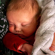 Parker is registered to the contest to win money with this photo: baby, blanket, closeup, comfort, cozy, cuddle, face, hair, hand, indoor, infant, newborn, peaceful, person, red_clothing, rest, skin, sleeping, soft_texture, warmth