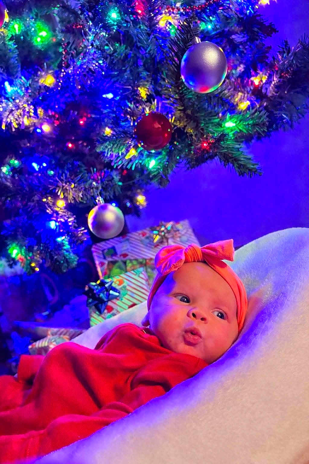 Parker joined the competition — help win amazing prizes! baby, infant, red_clothing, headband, bow, blanket, christmas_tree, christmas_lights, ornaments, presents, holiday, festive, decorations, indoors, soft_texture, cute, portrait, colorful, celebration, cozy