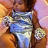 baby, infant, romper, mittens, leopard_print, cushion, pink, soft, chubby, cute, indoor, child, portrait, clothing, face, relaxing, person, curly_hair, baby_girl, seated